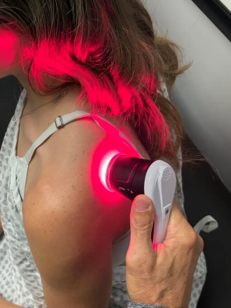 Aspen laser therapy delivering red light treatment to a patient's shoulder at Credence Chiropractic